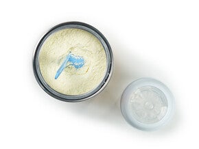 Open container of baby formula with a scoop next to the lid.