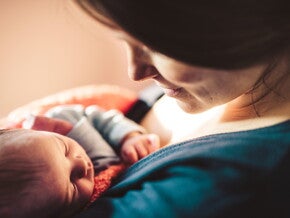 Мама нежно смотрит на младенца в объятиях