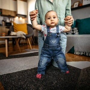 Мама допомагає немовляті стояти