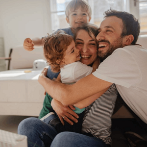 Щаслива родина, що сміється разом на дивані, відображає підтримку Nestlé FamilyNes для батьків.