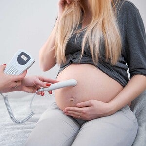 Ultrasound scan on pregnant woman's belly in clinic.