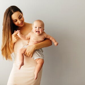 Мама держит на руках улыбающегося младенца