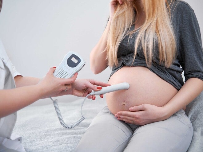 Doctor performing ultrasound on pregnant woman's belly.